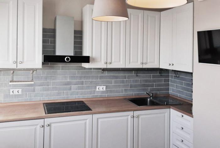 Cucina bianca in stile classico moderno con piano di lavoro in legno e grembiule grigio