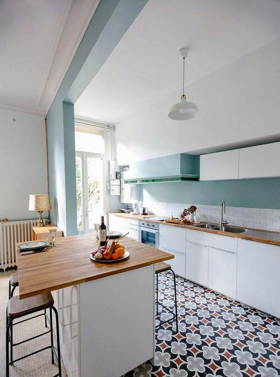 Cucina design in bianco e turchese con motivi sul pavimento.